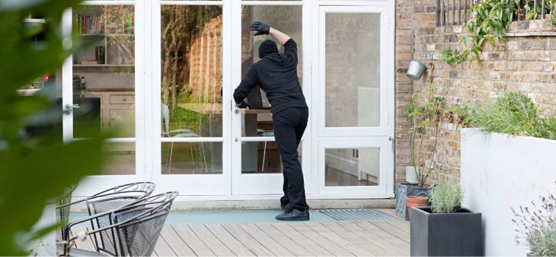 burglar looking through door at the back patio of a home