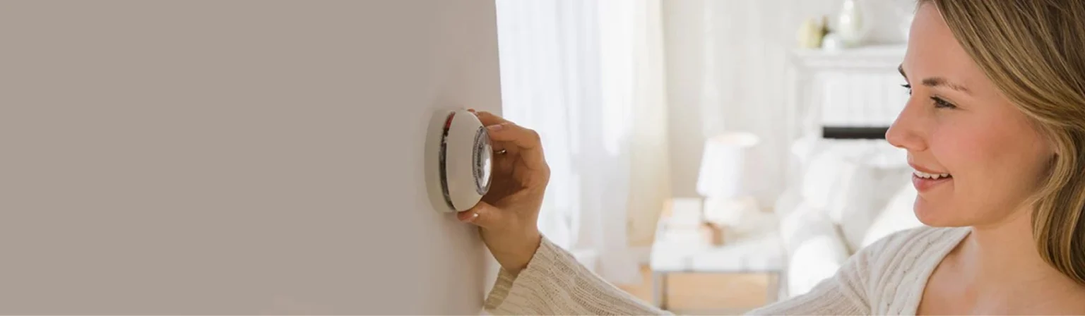 woman adjusting temperature on old thermostat